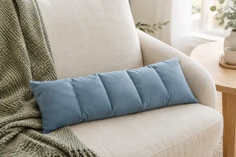 Coussin bouillotte sec bleu en coton, allongé et compartimenté, posé sur un fauteuil en lin clair